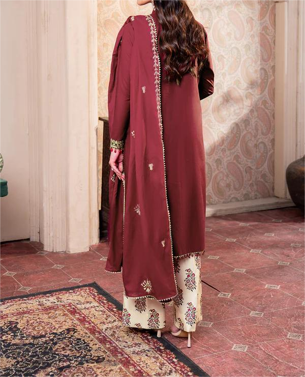 Maroon traditional outfit with intricate patterns on a patterned carpet