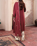 Maroon traditional outfit with intricate patterns on a patterned carpet