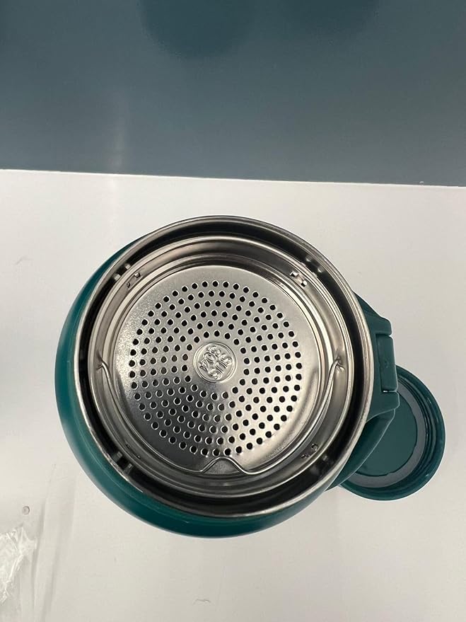 Teal mug with metal filter on a white surface