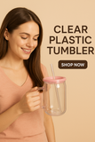 Woman holding a clear plastic tumbler with a pink lid and straw, on a beige background.