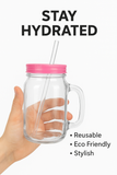 Hand holding a clear glass jar with a pink lid and straw, labeled 'Stay Hydrated'.