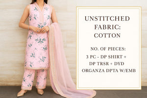 Woman wearing a light pink floral dress with a matching dupatta against a textured white wall.